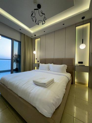 a bedroom with a large white bed with a large window at برج داماك الكورنيش جدة - Damac Tower Corniche Jeddah in Jeddah