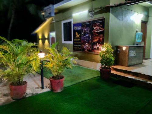 a room with three potted plants in front of a building at Xavier's guesthouse Wi-Fi and Villa in Colva