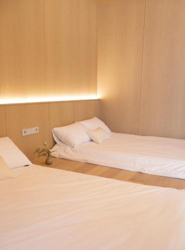 two beds in a small room with white sheets at THE EXTAY Lounge Jongno in Seoul