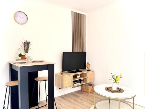 un soggiorno con TV, tavolo e sedie di L'Écrin d'Or - Élégant & Confortable- Idéalement Situé en Centre-Ville - Terrasse - Gare à 5 min a Valence