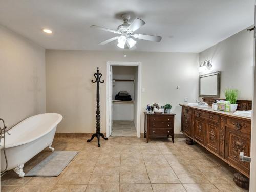 baño con bañera y ventilador de techo. en Pool, Spa&Lake 16 beds 8 bathrooms 50 car parking VENUE Magnolia Texas, en Magnolia