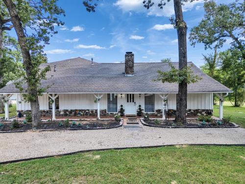 una casa blanca con árboles delante en Pool, Spa&Lake 16 beds 8 bathrooms 50 car parking VENUE Magnolia Texas, en Magnolia