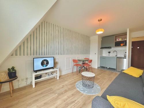 a living room with a television and a table with chairs at Sea view Studio, fully-equipped, TV & WiFi in Villers-sur-Mer