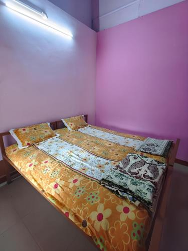 a bedroom with two beds and a pink wall at Gawade Niwas in Corgao