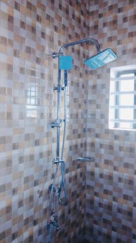 a shower in a bathroom with a tiled wall at Cozy II Studio with AC and kitchen in Abomey-Calavi