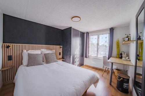 a bedroom with a large white bed and a desk at Idéal pour la famille proche du Futuroscope in Jaunay-Marigny