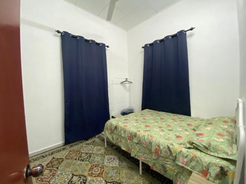 a small bedroom with blue curtains and a bed at Obah Homestay Kota Bharu in Kota Bharu