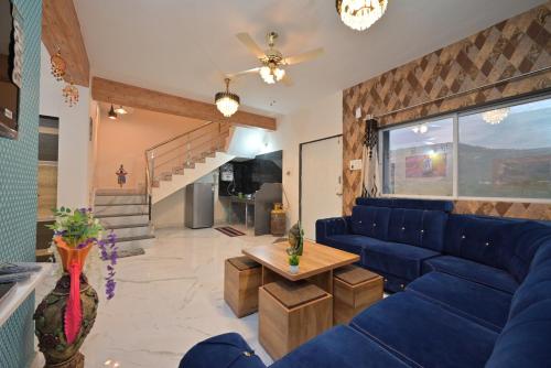 a living room with a blue couch and a table at ll EMPYREAN STAY ll LEONCINO VILLA II 4BHK ll AC ll LARGEST POOL ll in Lonavala