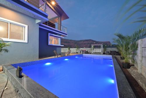 a blue swimming pool in front of a house at ll EMPYREAN STAY ll LEONCINO VILLA II 4BHK ll AC ll LARGEST POOL ll in Lonavala