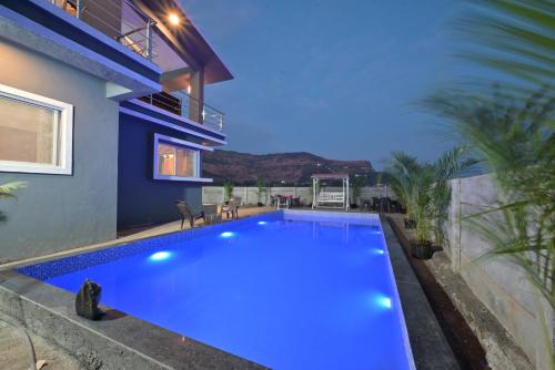 a blue swimming pool in front of a house at ll EMPYREAN STAY ll LEONCINO VILLA II 4BHK ll AC ll LARGEST POOL ll in Lonavala