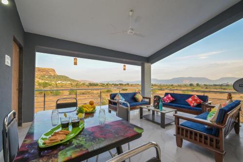 a living room with a table and chairs and a view at ll EMPYREAN STAY ll LEONCINO VILLA II 4BHK ll AC ll LARGEST POOL ll in Lonavala