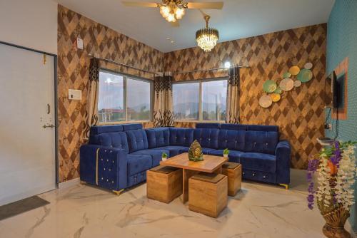 a living room with blue couches and a table at ll EMPYREAN STAY ll LEONCINO VILLA II 4BHK ll AC ll LARGEST POOL ll in Lonavala