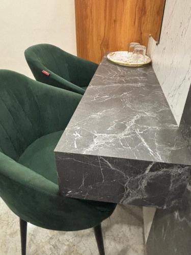 a black marble table and a green chair at The Golden Inn in Lucknow