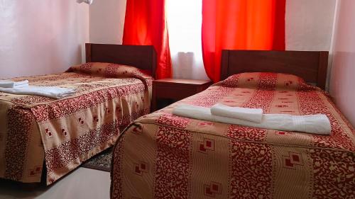 two beds in a room with red and orange curtains at Sadili Oval B & B in Nairobi