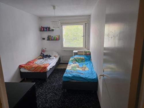 Dos camas en una habitación pequeña con ventana. en Aslan Home, en Gotemburgo