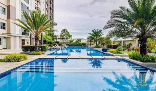 a swimming pool at a resort with palm trees at Evan's pad, Horizons 101 T1 in Cebu City