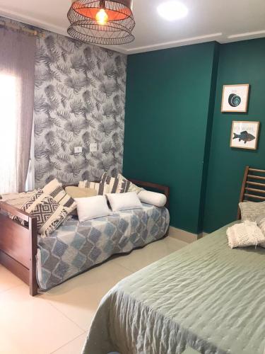 a bedroom with two beds and a green wall at Edifício Panoramique 180 Graus, Cobertura in Guarujá