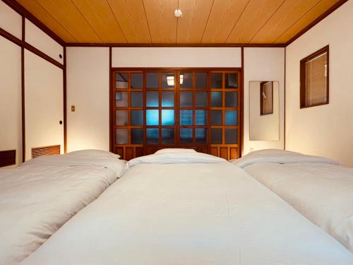 two beds in a room with a window at CASA de RandN Nakama 1F in Onna