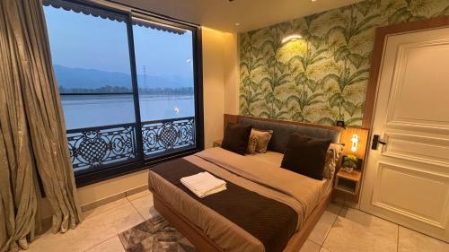 a bedroom with a bed and a large window at Evara By The Ganges in Rishīkesh