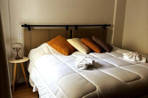 a white bed with pillows on it in a room at Apartamento Centro Serra Negra in Serra Negra