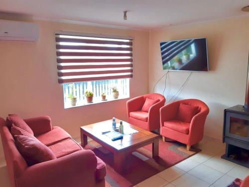 a living room with two red chairs and a tv at Acogedora casa en Puerto Varas in Puerto Varas