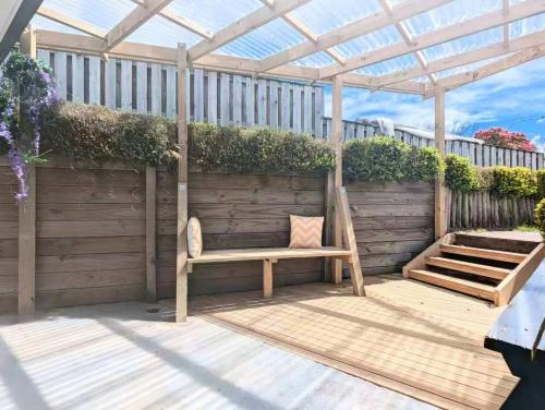 a wooden bench sitting under a pergola on a patio at 2 bedrooms, easy to start your journey in Rotorua