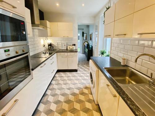 a kitchen with white cabinets and a sink at Bournemouth Beach Boutique with Hot Tub in Bournemouth