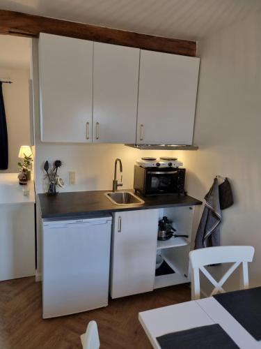 a kitchen with white cabinets and a sink at Mini-lejlighed med køkken - Deler bad og toilet med nabolejlighed 4 in Asperup