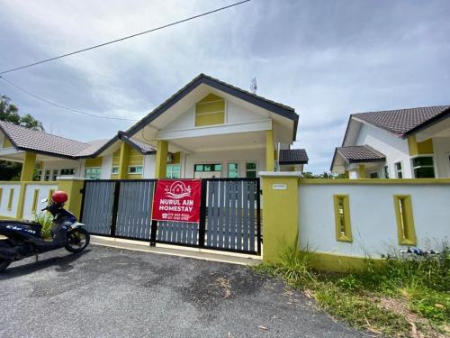 a motorcycle parked in front of a house with a gate at Nurul Ain Homestay, Kerengga Island, Marang in Marang