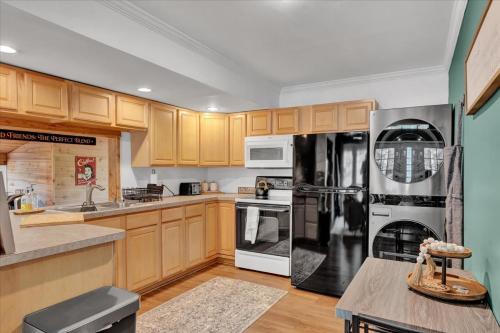 een keuken met houten kasten en een zwarte koelkast bij Tranquil Trails Cottage Fire Pit Cozy 3BDR in Gouldsboro