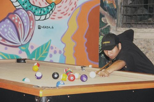 a man playing a game of pool with a cue at El Dragon Hotel in San Marcos La Laguna