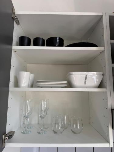 a white cabinet with wine glasses and bowls and plates at Charmant studio à 5 min de la Gare du Midi, 1-2 pe in Mellet
