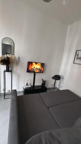 a living room with a tv on a white wall at Charmant studio à 5 min de la Gare du Midi, 1-2 pe in Mellet