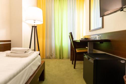 a hotel room with a bed and a desk and a lamp at Hotel Arkada in Levoča