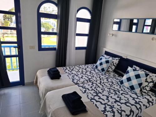 a bedroom with two beds and two windows at Casa Romantico - Playmar - Maspalomas in Maspalomas