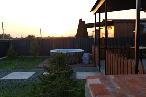 a backyard with a hot tub and a fence at Sky Cabins Ranch in Gamarjveba