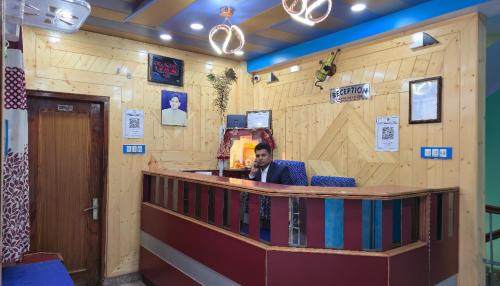 シムラーにあるHotel Tirupati Inn Hill Viewの木の壁のある部屋のバーカウンターに座っている男性