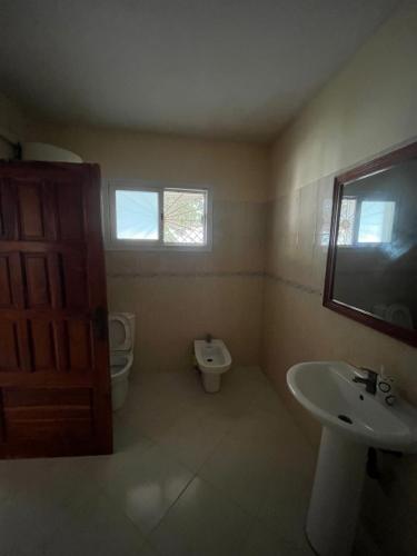 a bathroom with a sink and a toilet and a window at Résidence Cheikh in Ngaparou