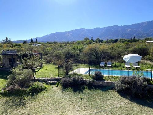 une piscine avec un parasol et des chaises et des montagnes dans l'établissement Casa de Las Brujas Traslasierra, à Los Molles