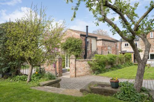 a brick house with a courtyard and trees at Tanyard Cottage - Whixley, York, North Yorkshire in York