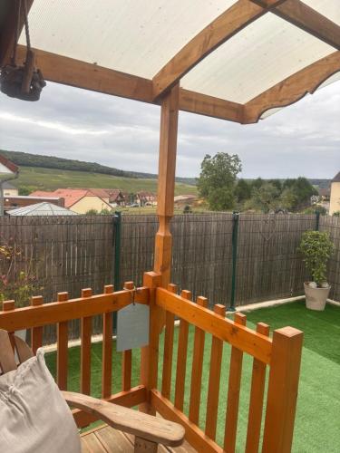 a wooden deck with a pergola and a fence at La Galipette, charmant chalet en Champagne in Fleury-la-Rivière