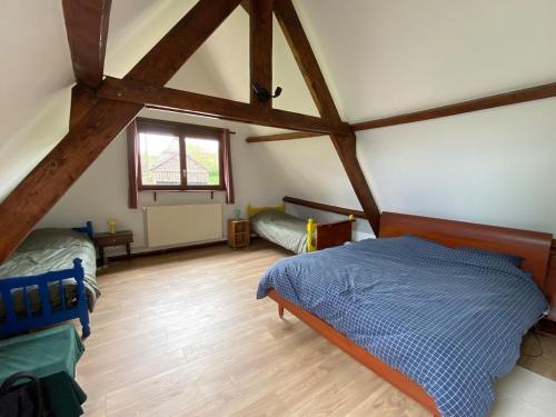 a attic bedroom with two beds and a window at Charmante longère percheronne avec cheminée, jacuzzi et verger in Charbonnières