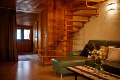 a living room with a green couch and wooden stairs at Hotel Nufenen in Ulrichen