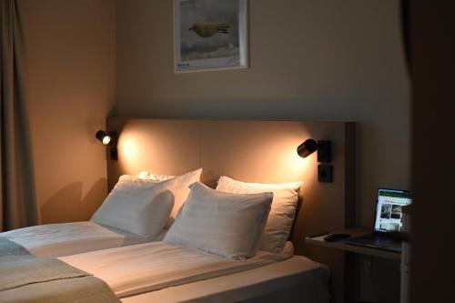 a bedroom with a bed with white pillows and a laptop at Hotel Local 101 in Reykjavík