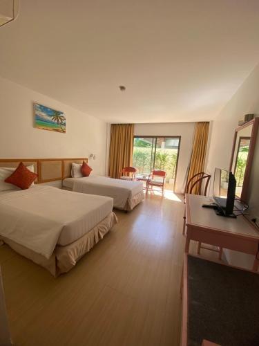 a hotel room with two beds and a desk at Nautical Inn in Pattaya