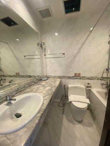 a white bathroom with a sink and a toilet at Nautical Inn in Pattaya Central