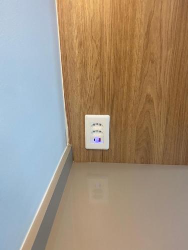 a white electrical outlet on a wooden wall at Apto novo perto da UFF e Plaza in Niterói