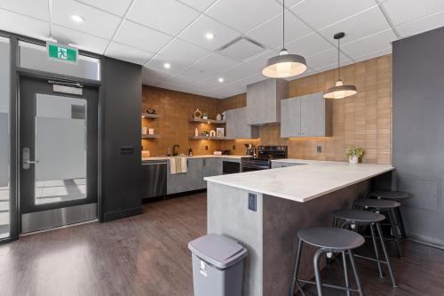 a large kitchen with a counter and stools in it at Central Kelowna TOP FLOOR rooftop patio in Kelowna