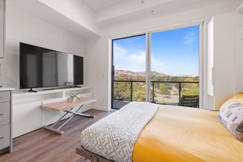 a bedroom with a large bed and a large window at Central Kelowna TOP FLOOR rooftop patio in Kelowna