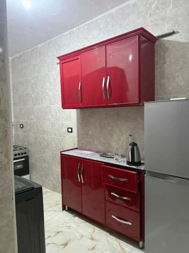 eine Küche mit roten Schränken und einem weißen Kühlschrank in der Unterkunft Marco inn in Amman